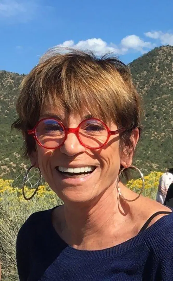 A woman with red glasses smiling for the camera.