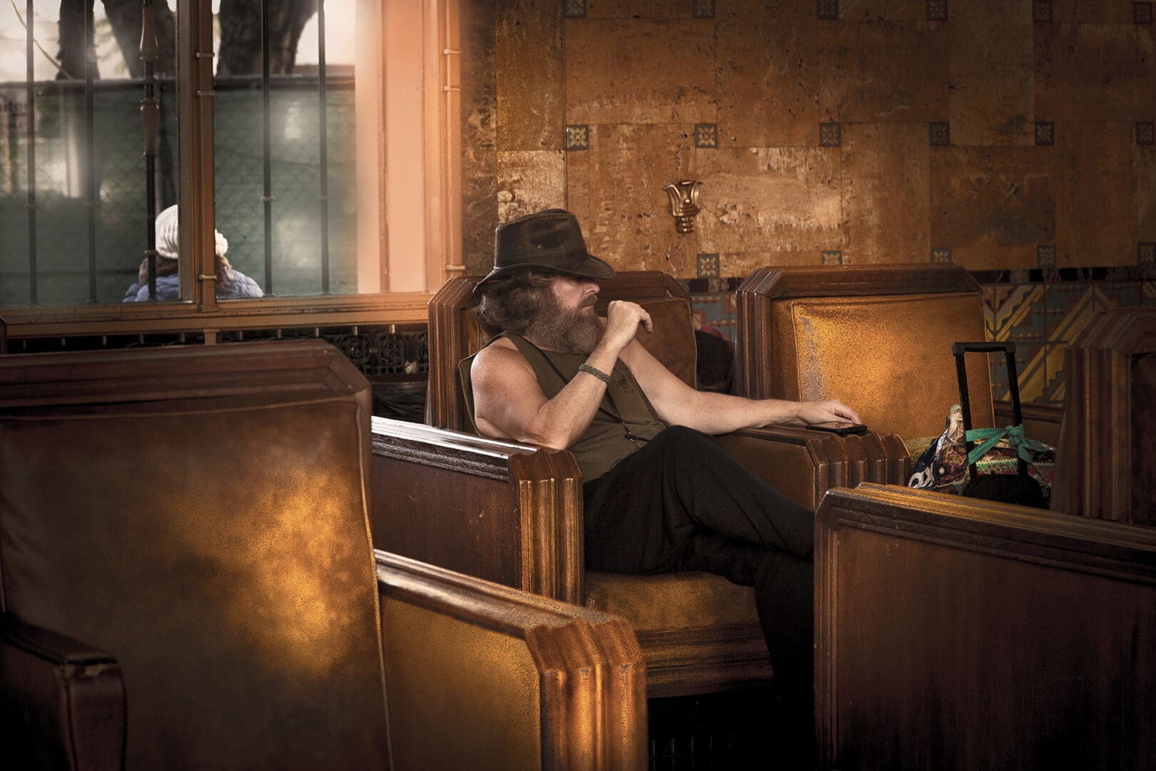 A man sitting in an old church with his hand on the chair.