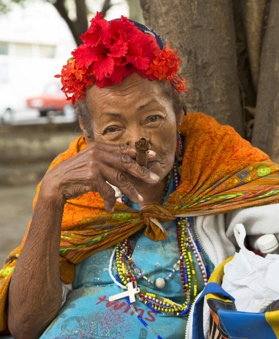 A woman with red flowers in her hair smoking.