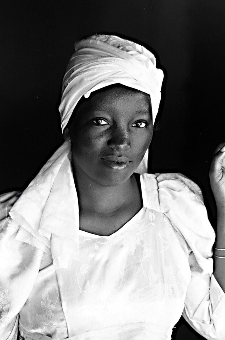 A black and white photo of a woman wearing a head scarf.