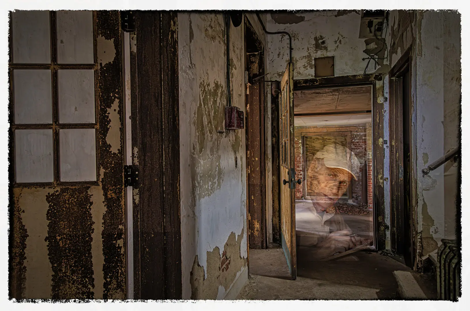 A room with peeling paint and a person in the doorway.