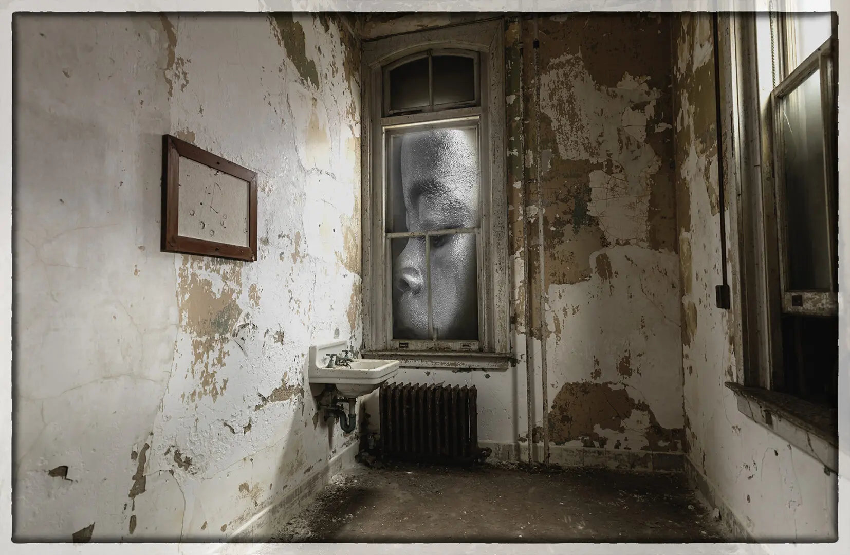 A room with peeling paint and a window.