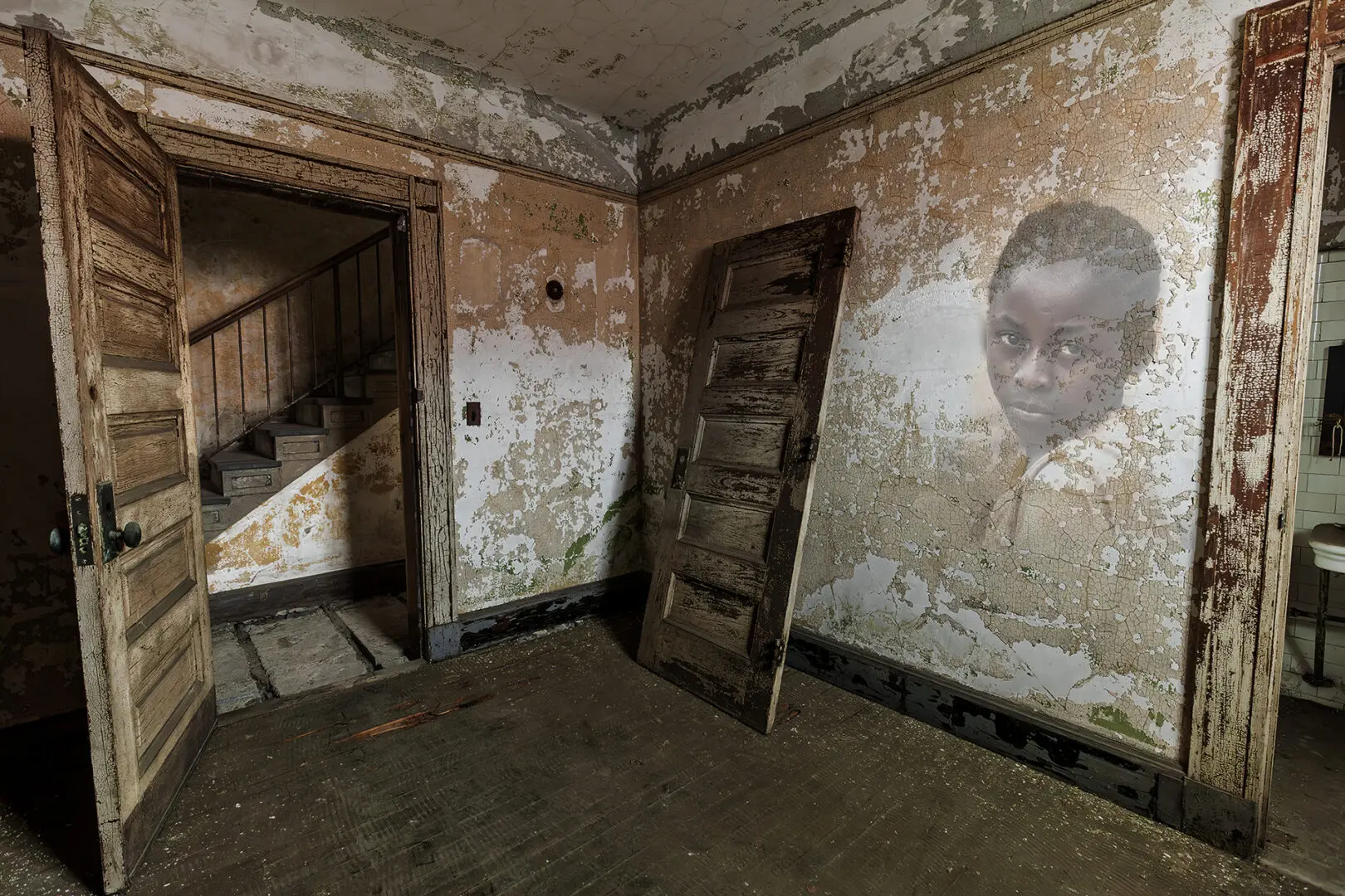 A room with peeling paint and a picture of a boy.