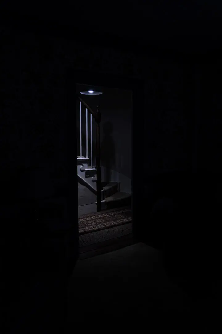 A dark room with a light shining on the door.