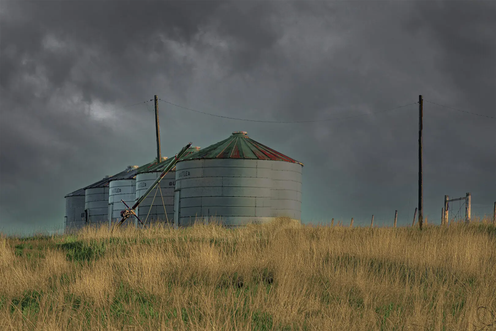 A grain bin sitting in the middle of a field.