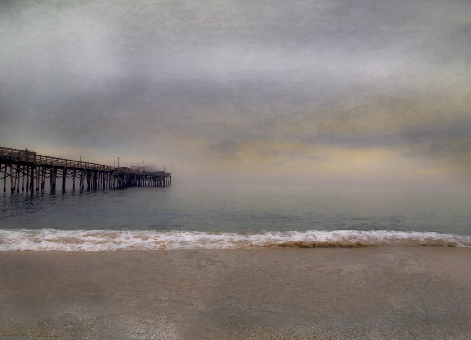 A pier is in the distance on the beach.