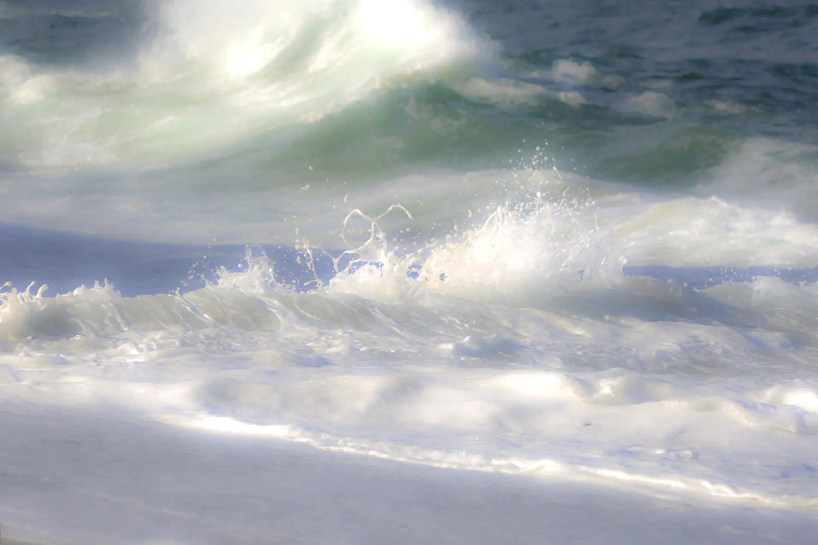 A wave is crashing on the beach as it hits the shore.