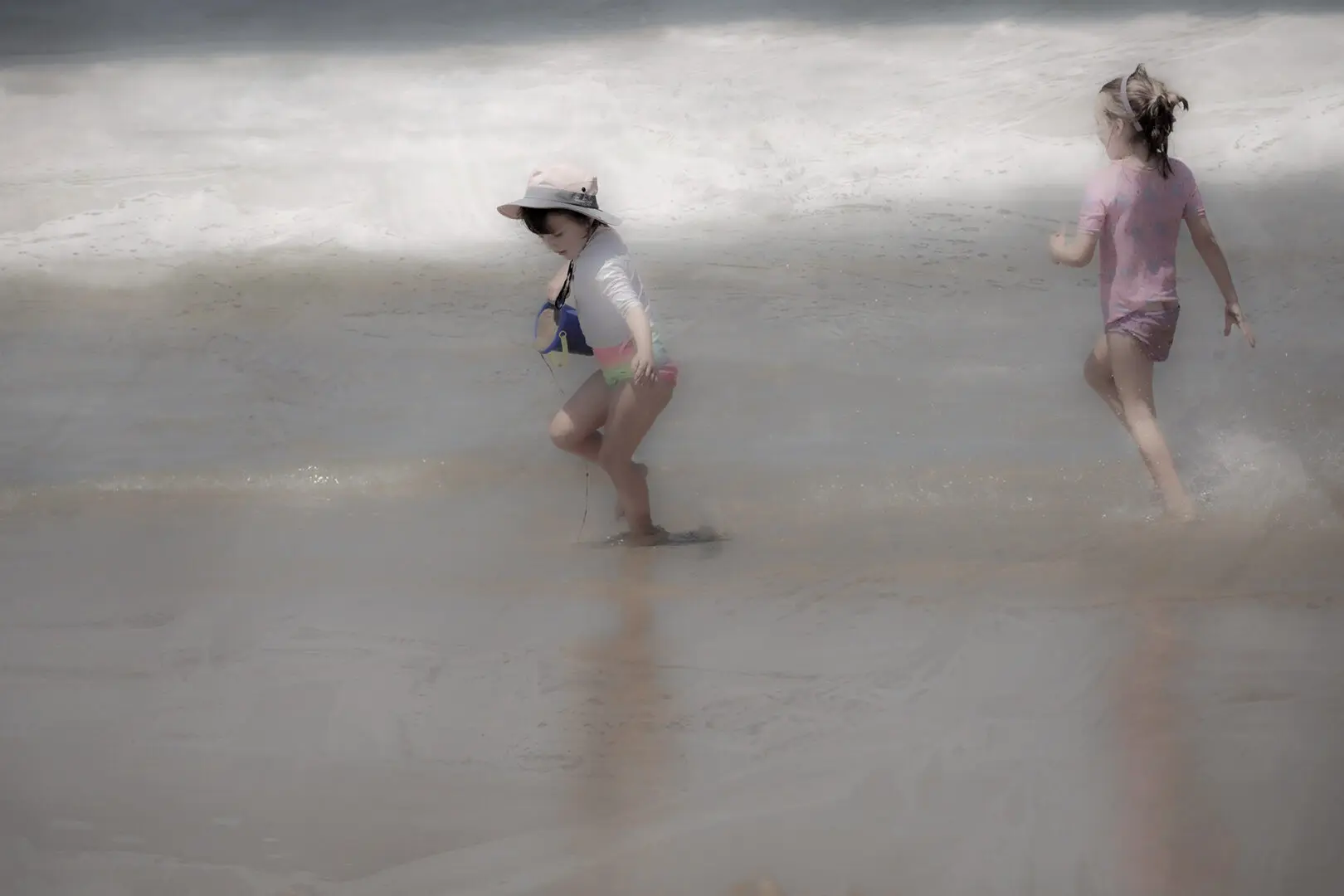 A blurry image of two children playing in the sand.