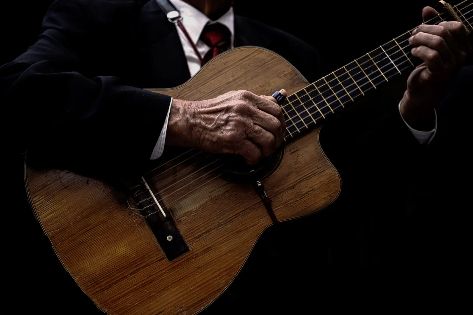 A person in a suit and tie playing an acoustic guitar.