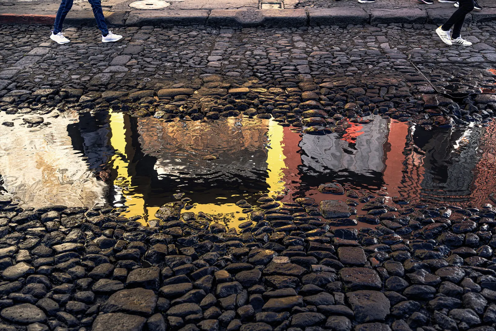 A puddle of water on the ground with a person standing in it.