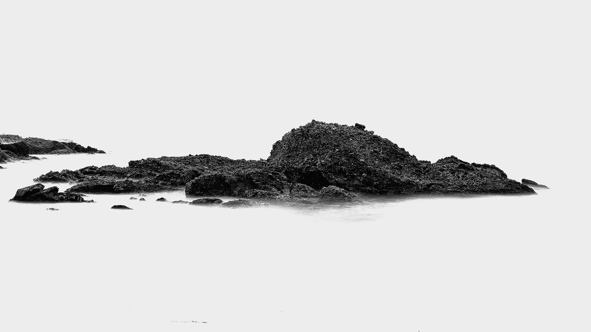 Black and white rocky shoreline with mist