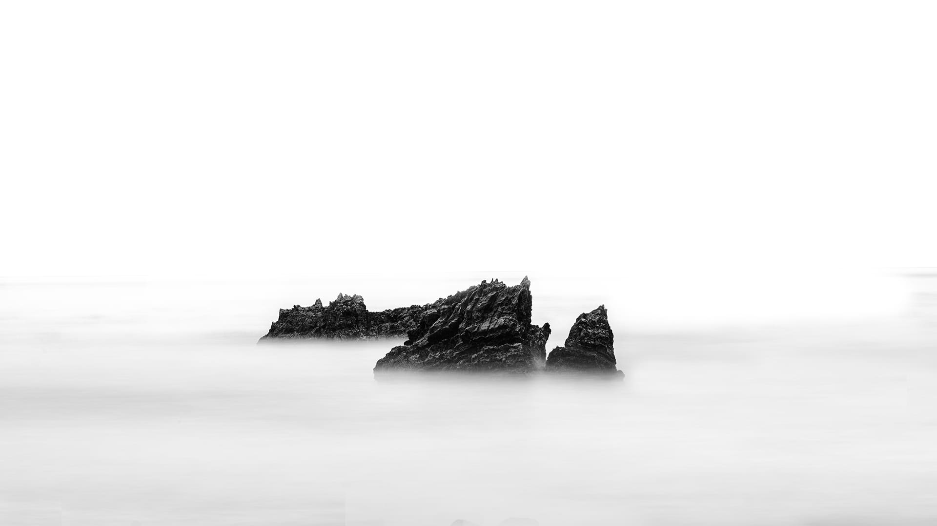 Jagged coastal rocks in misty long exposure