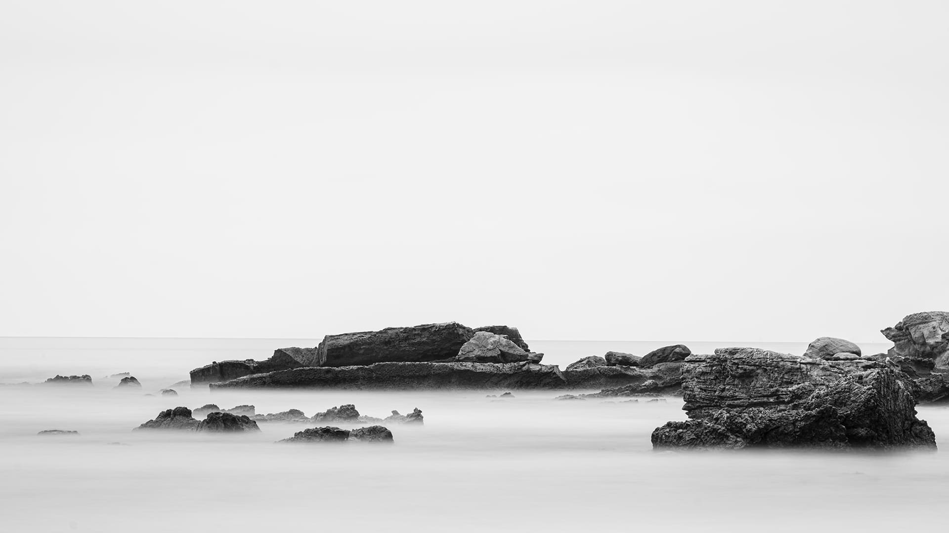 Black and white rocky shoreline with mist