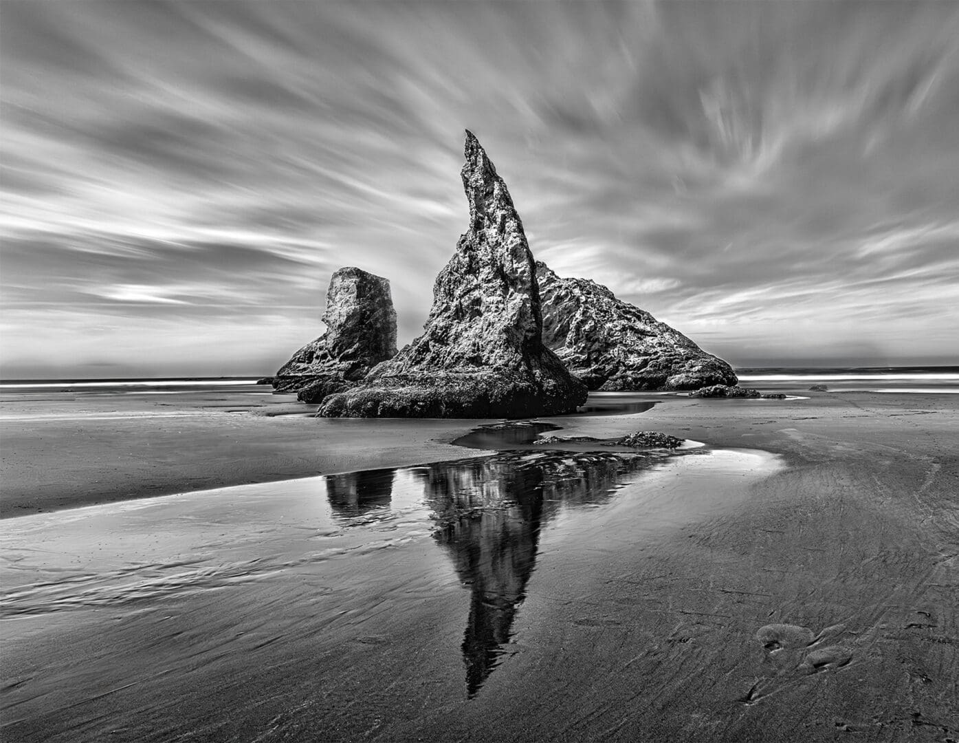 Monochrome sea stacks reflected on wet sand