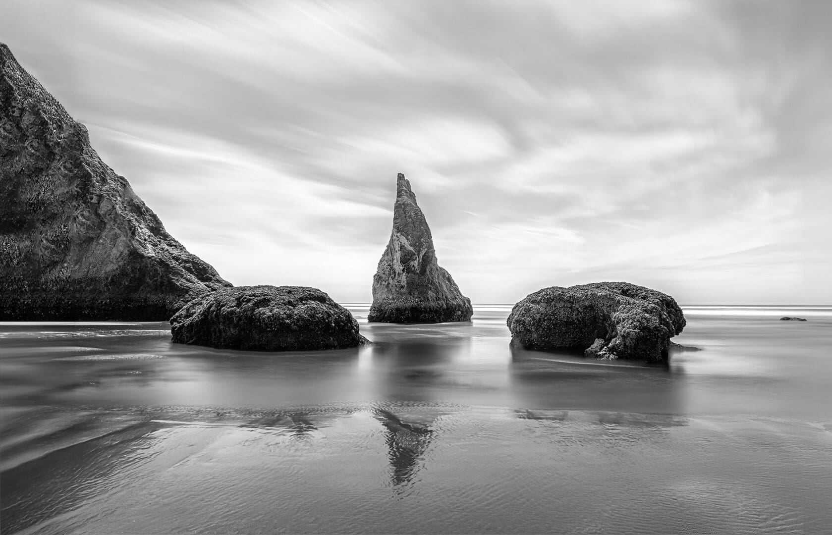 Monochrome sea stacks reflected on wet sand