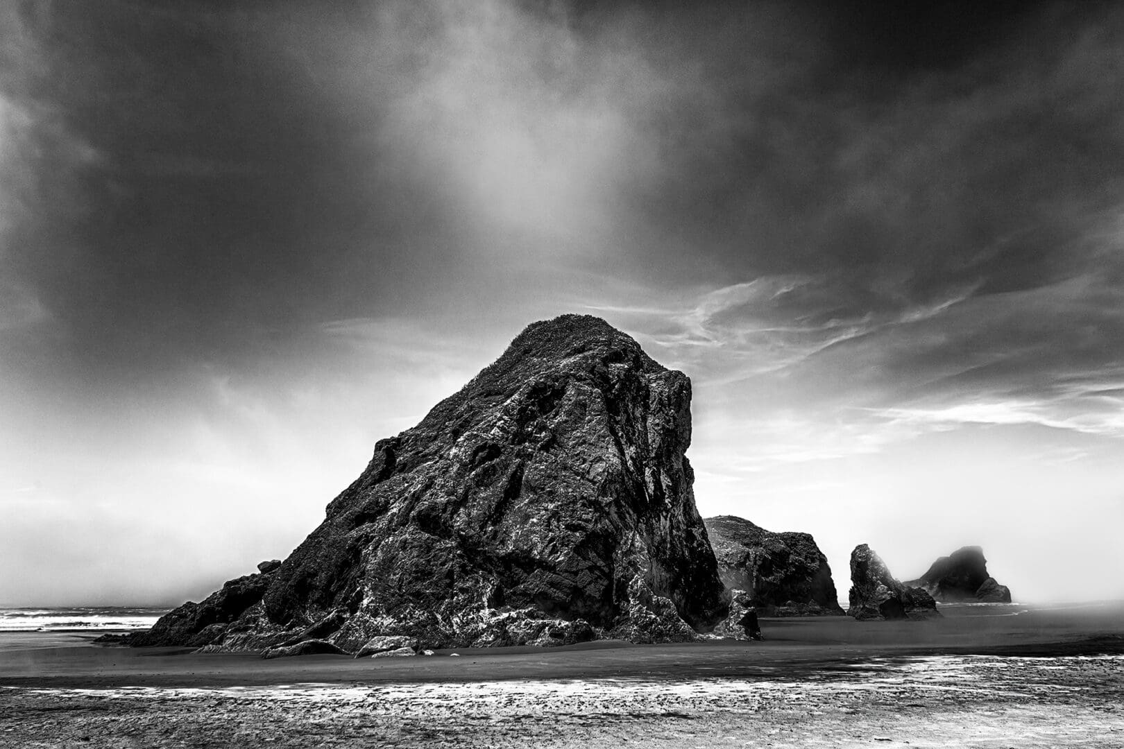 Large sea stack on misty beach