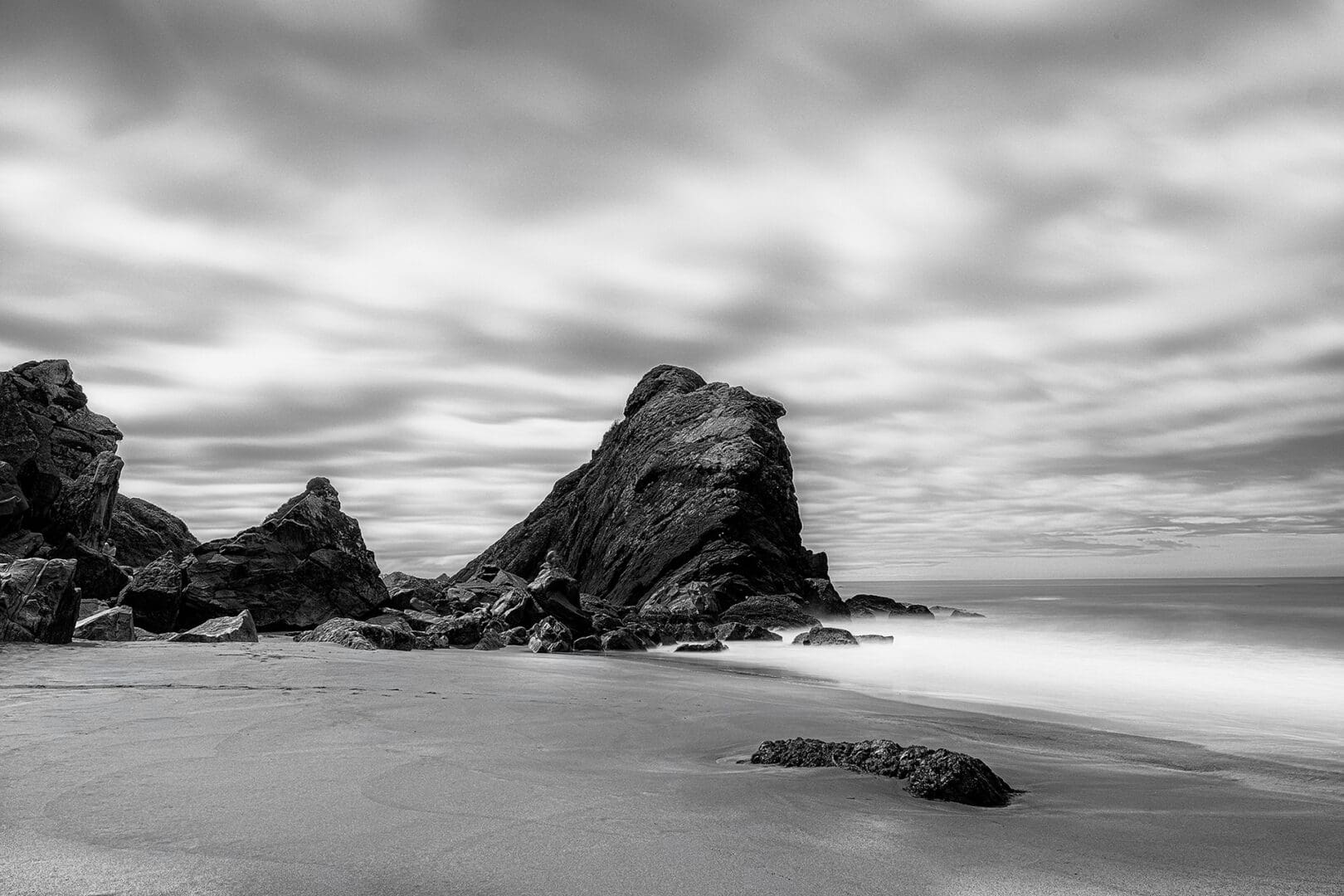 Monochrome beach with large rock formation